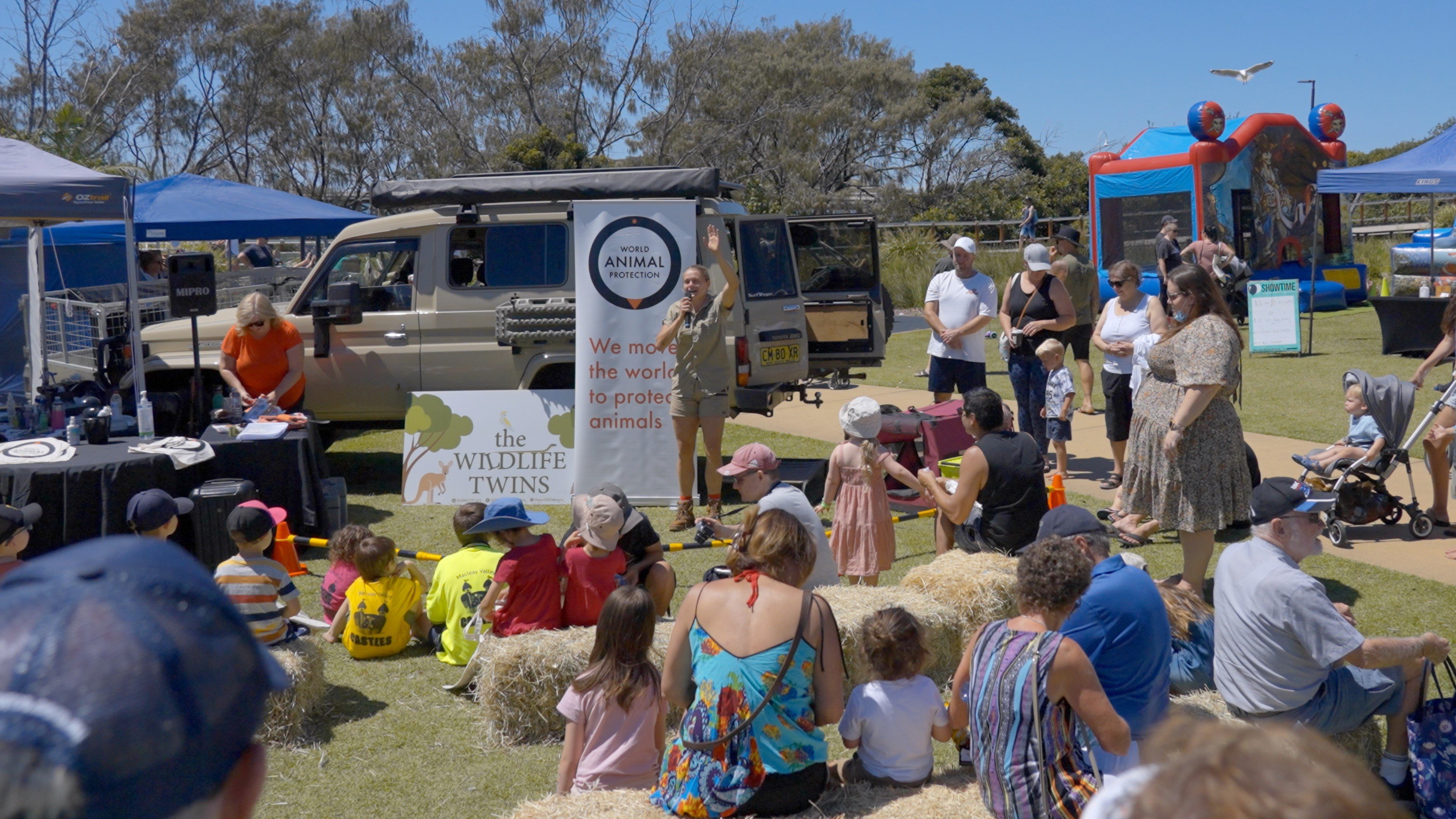 a group of people at an animal expo, listening to a speaker outside