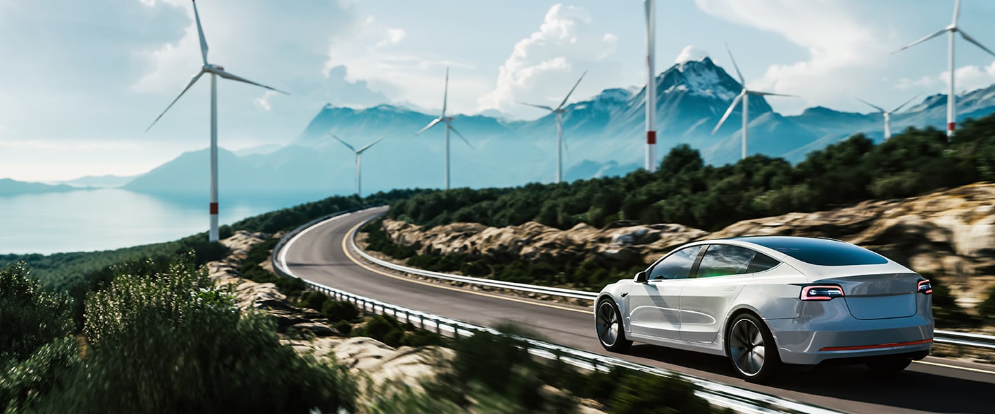 A Tesla driving on the road through a wind farm