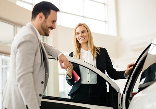 women and guy smiling looking at a car 