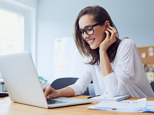 Women with glasses smiling looking at her laptop