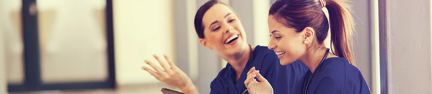 two females in scrubs talking and smiling